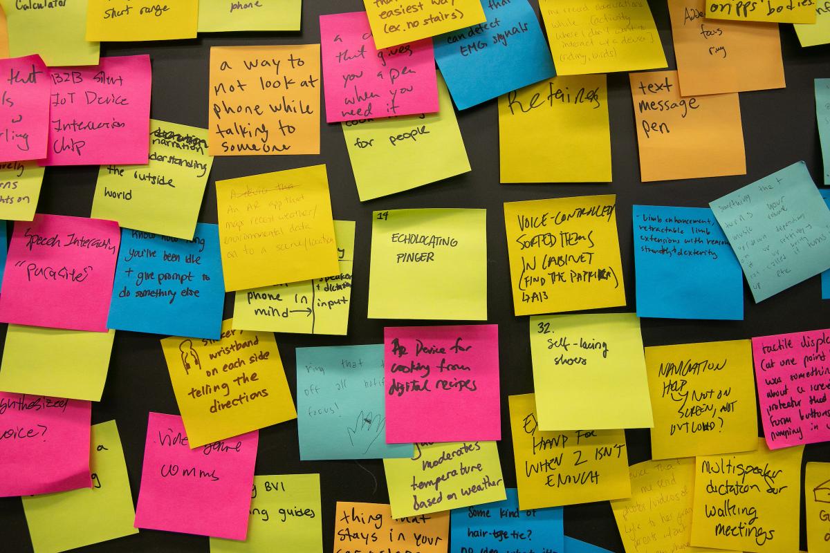 An arrangement of multi-colored sticky notes adorn a classroom wall. An arrangement of multi-colored sticky notes adorn a classroom wall.